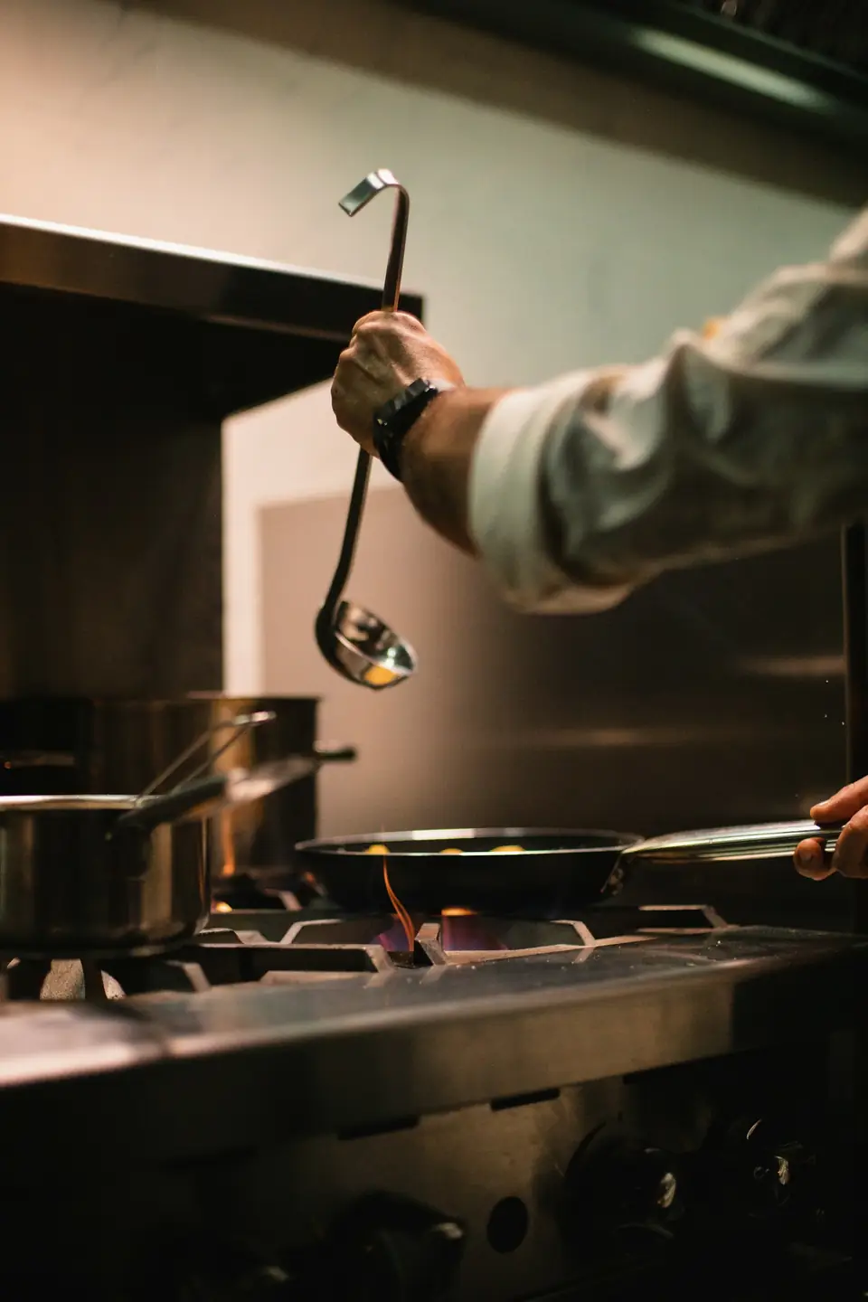 Louche et casseroles sur le piano de cuisson, flamme sous une poêle
