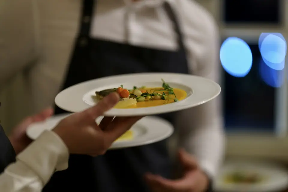 Serveur apportant deux assiettes en salle, dans une lumière tamisée