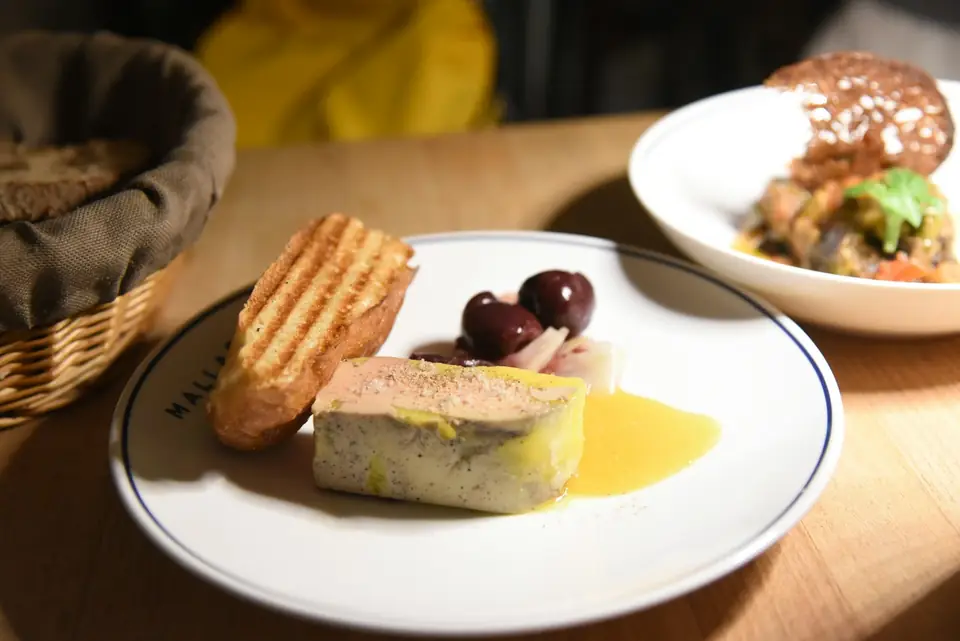 Tranche de foie gras mi-cuit servie avec du pain grillé et des olives