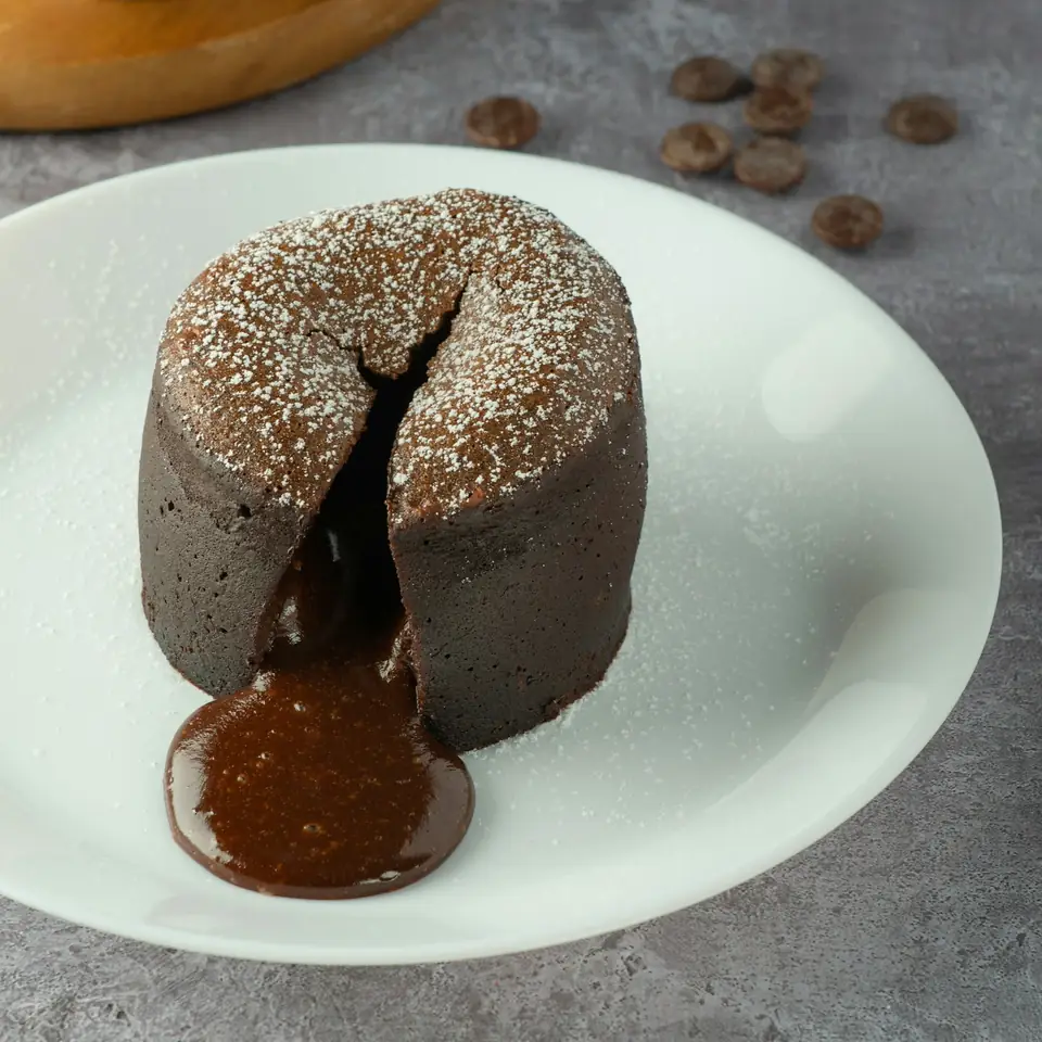Fondant au chocolat ouvert, cœur coulant sur une assiette blanche