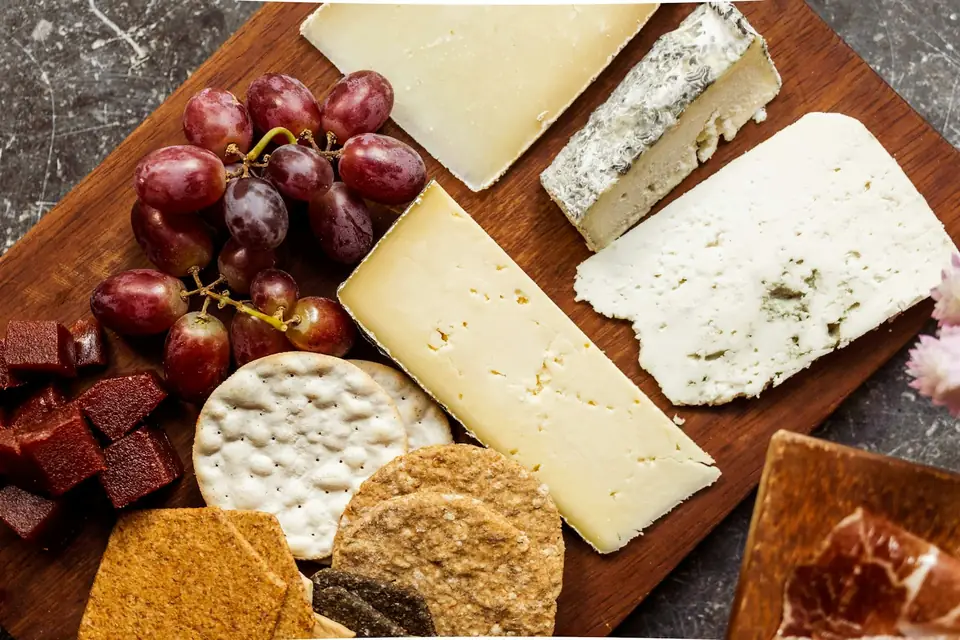 Planche de fromages variés accompagnés de raisin, de pâte de coing et de crackers
