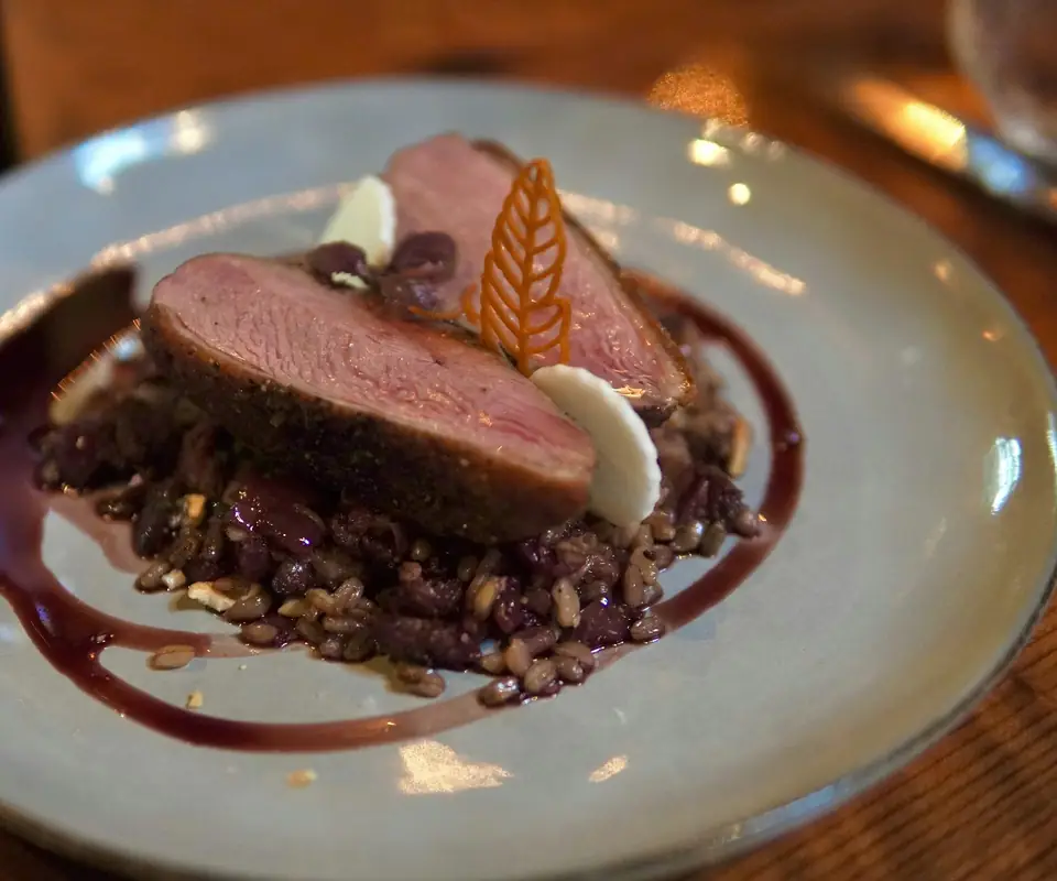 Magret de canard rosé, tranché sur un lit de lentilles, nappé d’un jus sombre