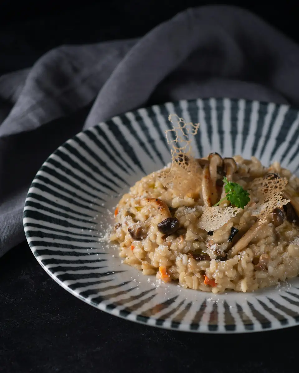 Risotto crémeux aux champignons dans une assiette à rayures